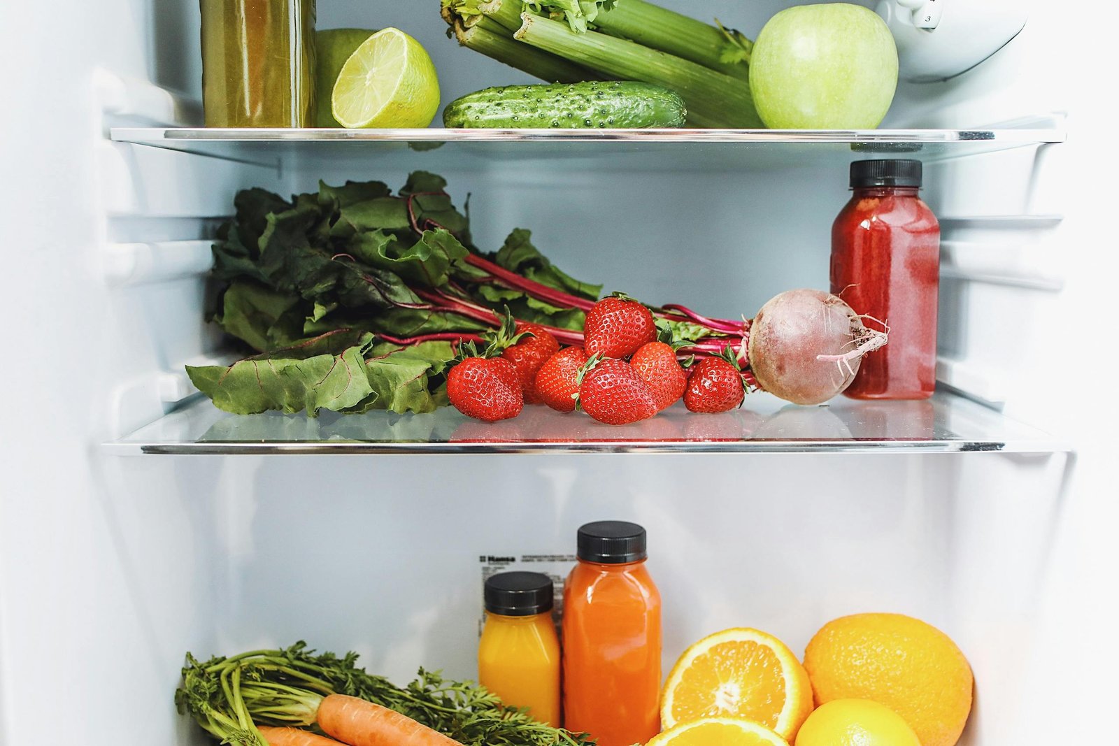 Colorful array of fresh fruits and vegetables neatly arranged in a refrigerator.