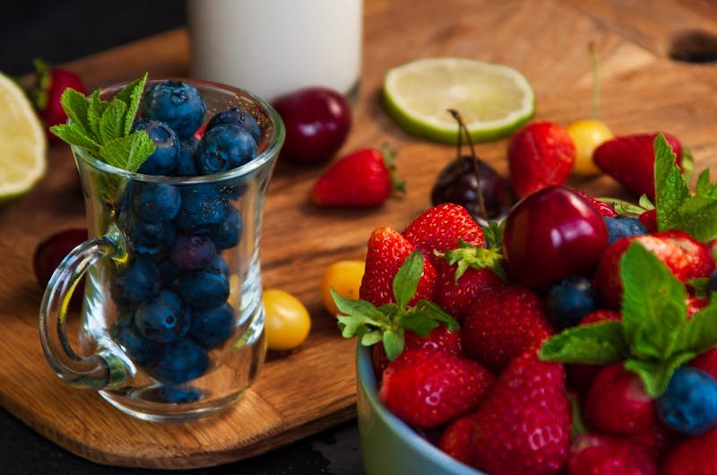 Vibrant display of blueberries, strawberries, and assorted fruits on a wooden board.